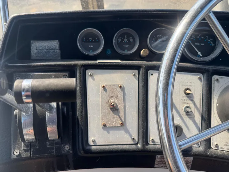 Slide: The Image of 1986 Carver Mariner 28 dashboard with steering wheel, gauges, and control levers. - 9