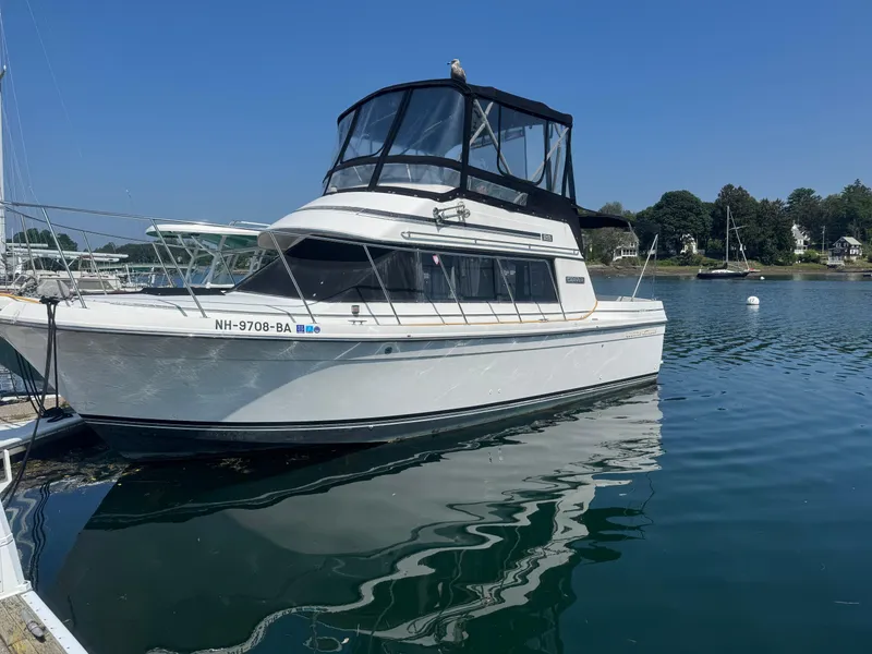 The Image of 1986 Carver Mariner 28 boat docked on calm water under clear blue sky. - 0