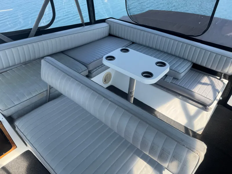 Slide: The Image of Interior of 1986 Carver Mariner 28 with cushioned seating and table on a sunny day. - 10