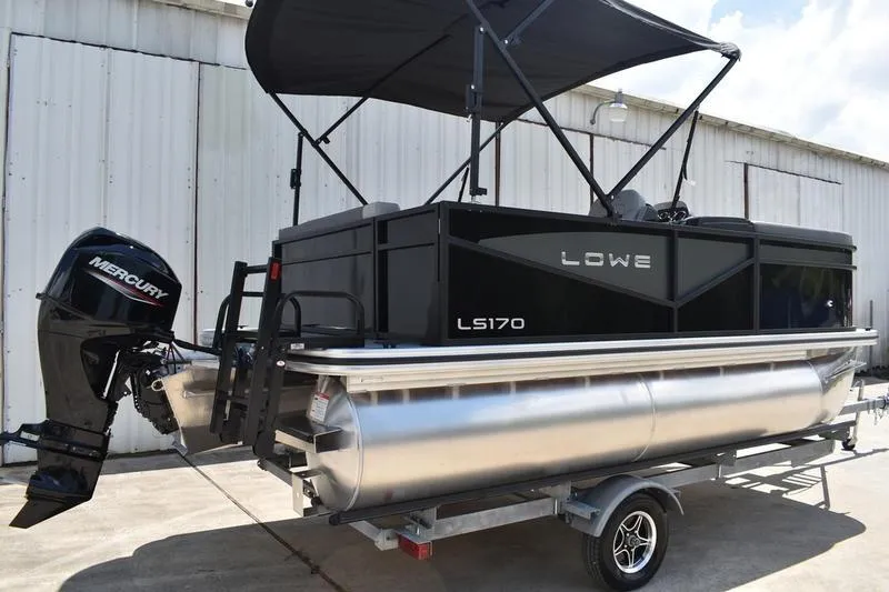 Slide: The Image of 2026 Lowe LS 170 pontoon boat on trailer, black exterior, parked outdoors. - 1