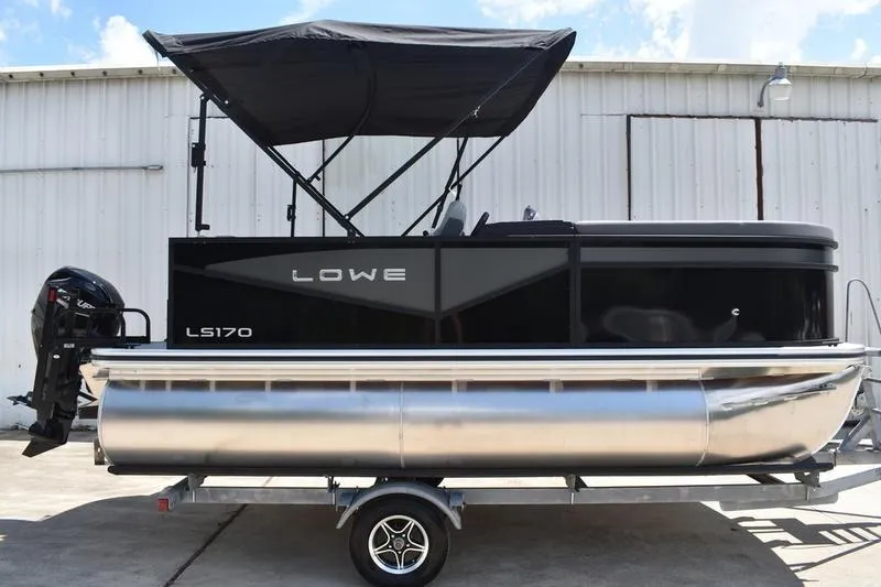 Slide: The Image of 2026 Lowe LS 170 pontoon boat with Mercury outboard motor, parked on trailer. - 2