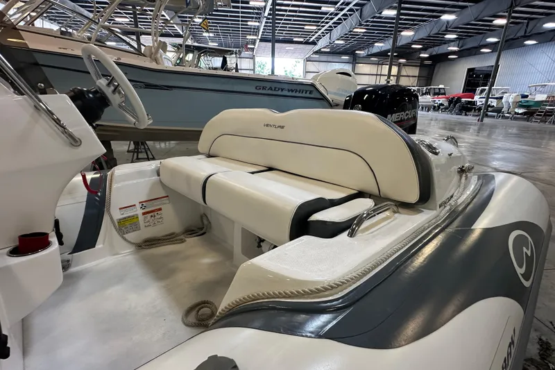Slide: The Image of 2022 Walker Bay Venture 16 boat interior with seating and steering wheel in a showroom. - 15