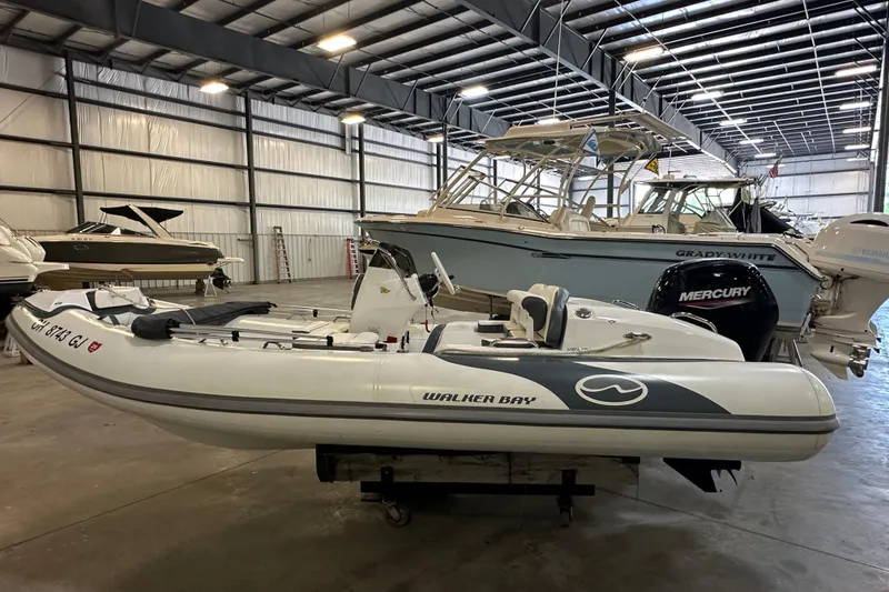 Slide: The Image of 2022 Walker Bay Venture 16 boat in indoor storage, surrounded by other vessels. - 3