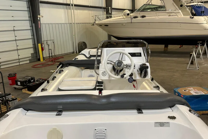 Slide: The Image of 2022 Walker Bay Venture 16 boat interior in a storage facility, showcasing steering console. - 6