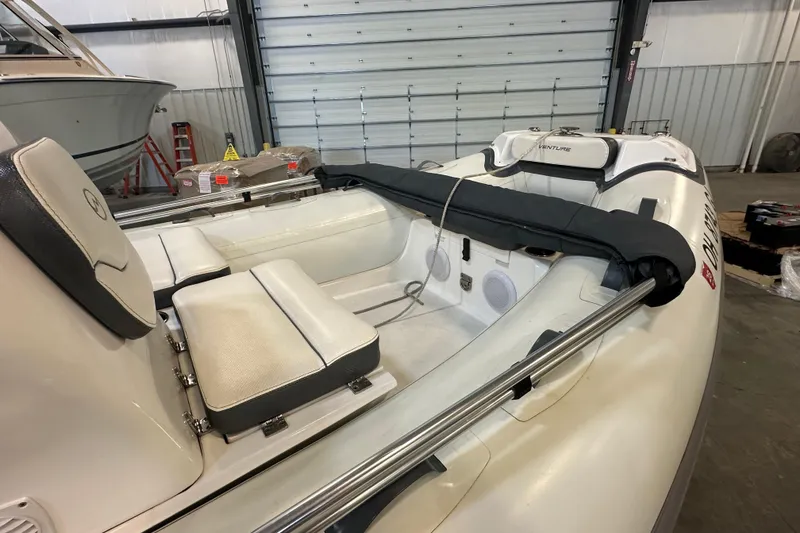 Slide: The Image of 2022 Walker Bay Venture 16 boat interior with cushioned seating in a garage setting. - 9