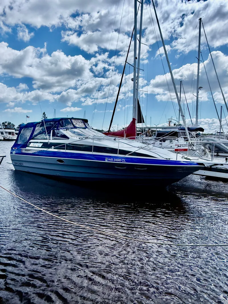 Slide: The Image of 1989 Bayliner Avanti 3255 Sunbridge docked under a partly cloudy sky. - 2