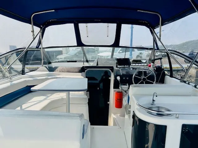 Slide: The Image of 1989 Bayliner Avanti 3255 Sunbridge cockpit with seating, steering wheel, and sink. - 3