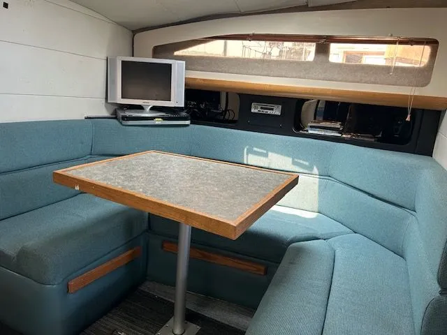 Slide: The Image of 1989 Bayliner Avanti 3255 Sunbridge interior with blue seating, table, and small TV. - 6