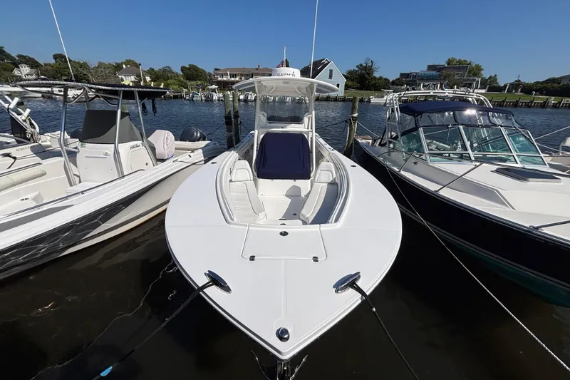 Slide: The Image of 2017 Regulator 28 boat docked between two other boats on a sunny day. - 2