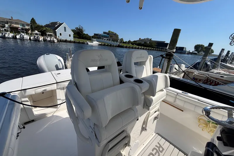 Slide: The Image of 2017 Regulator 28 boat with white seating, docked by waterfront homes. - 30