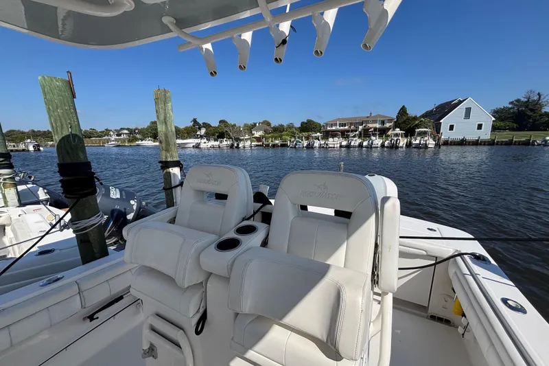 Slide: The Image of 2017 Regulator 28 boat with white seating, docked by waterfront homes. - 31