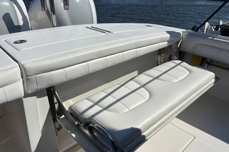 Slide: The Image of 2017 Regulator 28 boat with white cushioned seating and storage, docked by the water. - 48