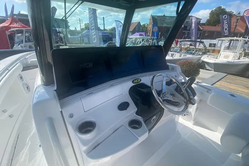 Slide: The Image of 2025 HCB 39 Speciale boat dashboard with steering wheel and controls at a marina. - 8