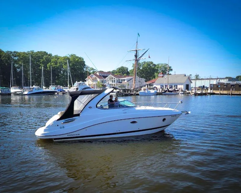 The Image of 2016 Rinker 290 Express boat cruising in a scenic marina setting. - 0