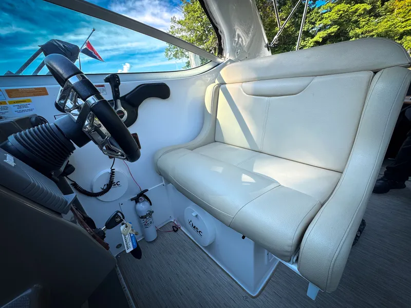Slide: The Image of 2016 Rinker 290 Express boat interior with steering wheel and beige seating. - 19