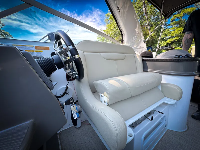 Slide: The Image of 2016 Rinker 290 Express boat interior with steering wheel and beige captain's seat. - 2
