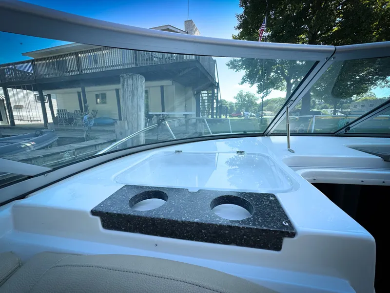 Slide: The Image of 2016 Rinker 290 Express boat interior with cup holders and windshield view. - 23