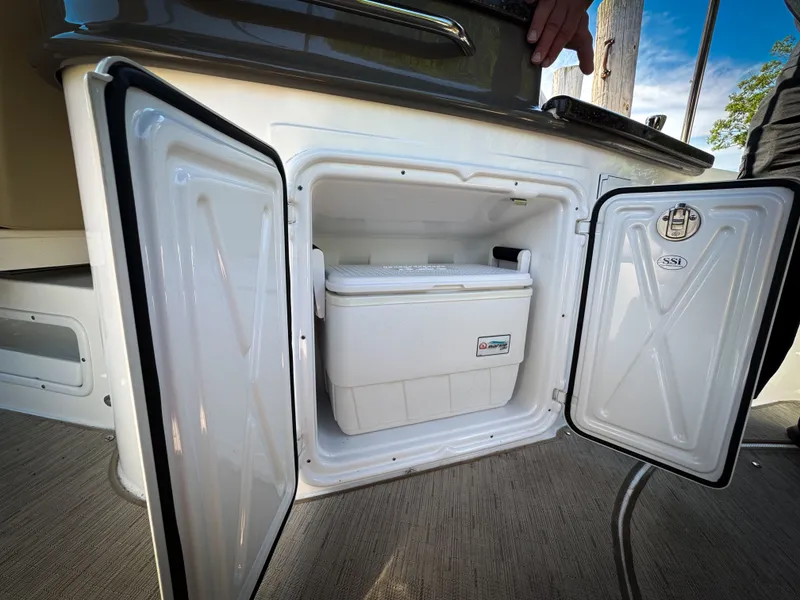 Slide: The Image of Open storage compartment on 2016 Rinker 290 Express boat with cooler inside. - 32