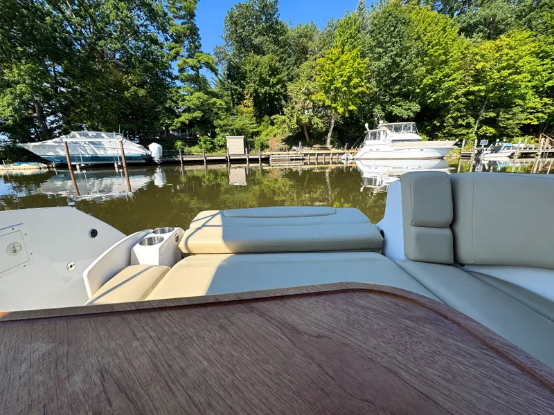 Slide: The Image of 2016 Rinker 290 Express boat interior with scenic marina view and surrounding trees. - 38