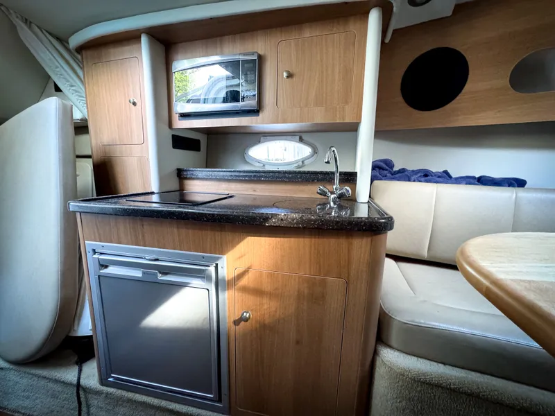 Slide: The Image of 2016 Rinker 290 Express cabin interior with kitchenette and seating area. - 4