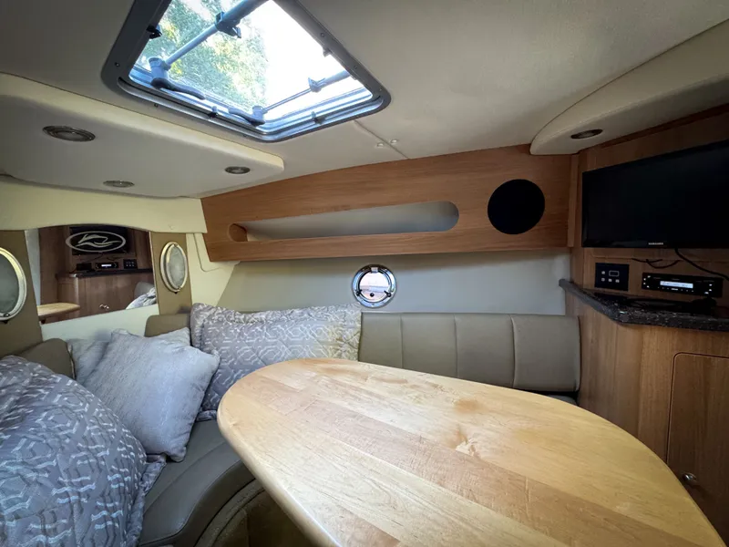 Slide: The Image of 2016 Rinker 290 Express cabin interior with seating, table, and porthole window. - 42