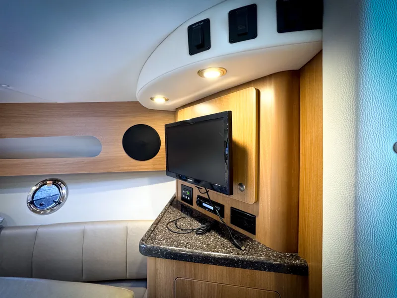 Slide: The Image of Interior of 2016 Rinker 290 Express boat with TV and modern wood paneling. - 44