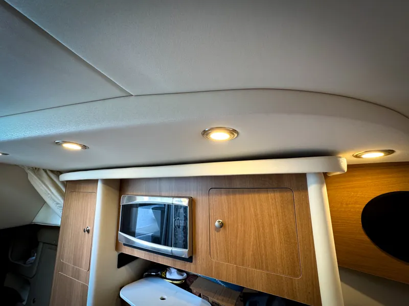 Slide: The Image of 2016 Rinker 290 Express cabin interior with microwave and wooden cabinetry. - 47
