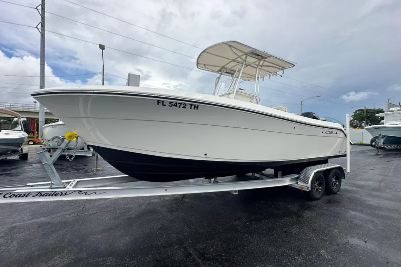Slide: The Image of 2022 Cobia 237 Center Console boat on trailer, parked outdoors under cloudy sky. - 11