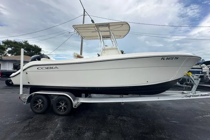Slide: The Image of 2022 Cobia 237 Center Console boat on trailer, parked outdoors. - 2