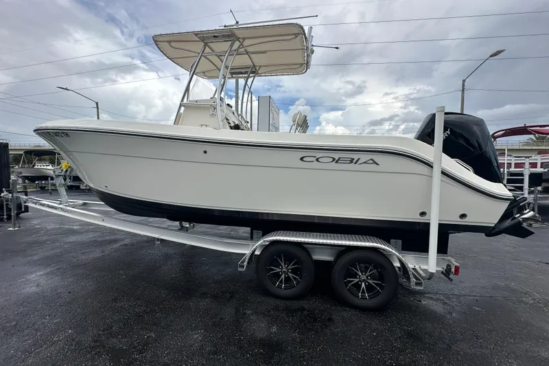 Slide: The Image of 2022 Cobia 237 Center Console boat on trailer, displayed outdoors under cloudy sky. - 9