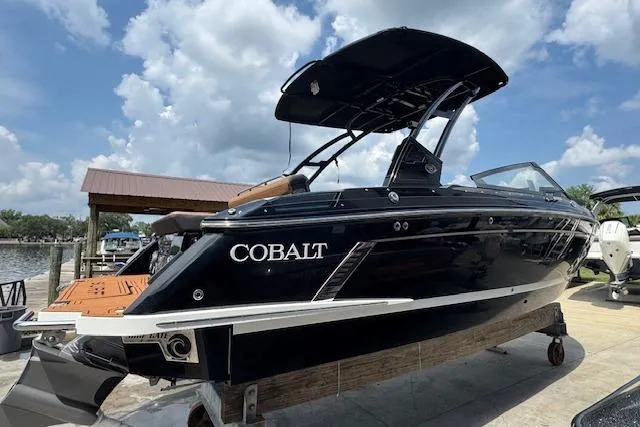 Slide: The Image of 2026 Cobalt R4 Surf boat on display, sleek black design, dockside under a blue sky. - 6