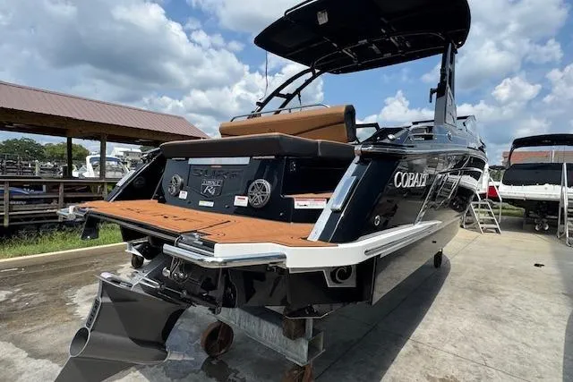 Slide: The Image of 2026 Cobalt R4 Surf boat with sleek design, docked under a cloudy sky. - 7