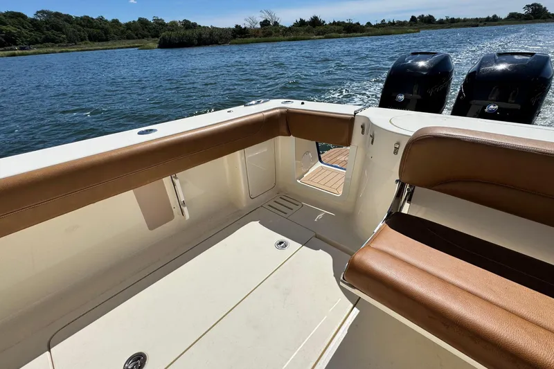 Slide: The Image of 2016 Scout 420 LXF boat interior with brown seating, dual engines, and scenic water view. - 14