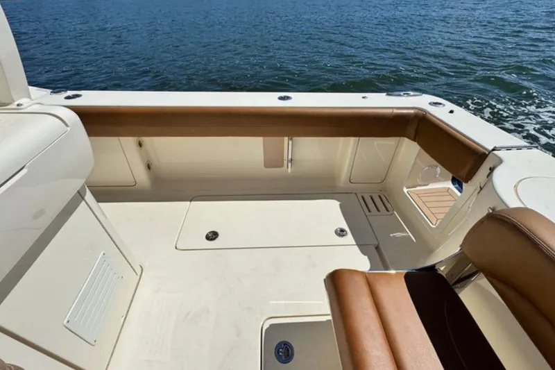 Slide: The Image of 2016 Scout 420 LXF boat interior with tan seating, overlooking water. - 15