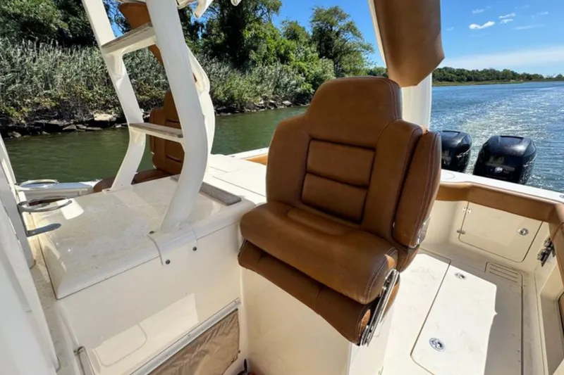 Slide: The Image of 2016 Scout 420 LXF boat interior with brown leather seating and scenic water view. - 26