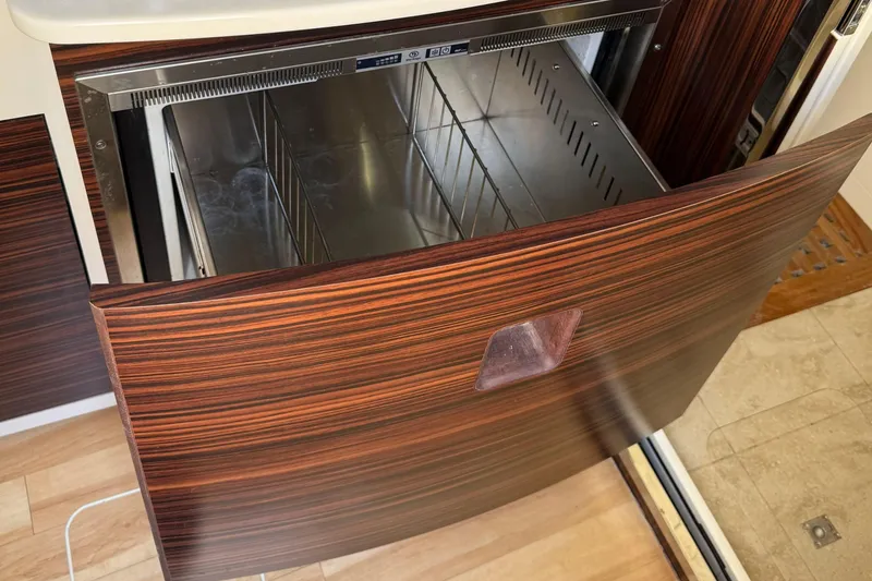 Slide: The Image of Open drawer refrigerator in 2016 Scout 420 LXF boat, featuring wood paneling and stainless steel interior. - 59