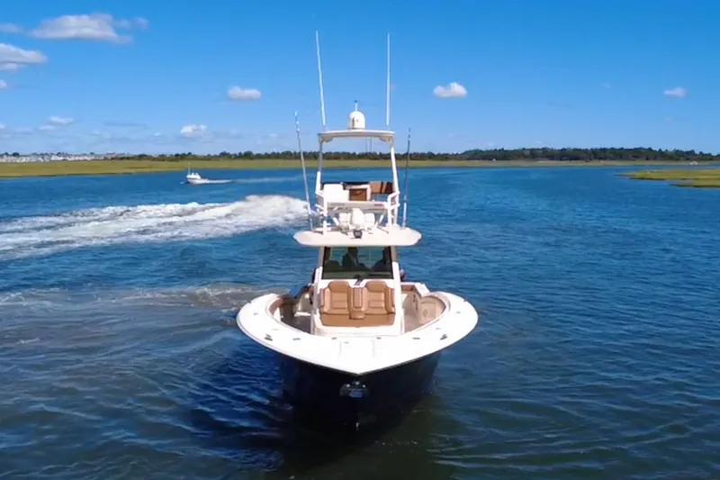 Slide: The Image of 2016 Scout 420 LXF boat cruising on a sunny day in a scenic waterway. - 8