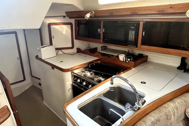 Slide: The Image of Interior of a 1991 Catalina 42 MkII sailboat kitchen with stove, sink, and microwave. - 2