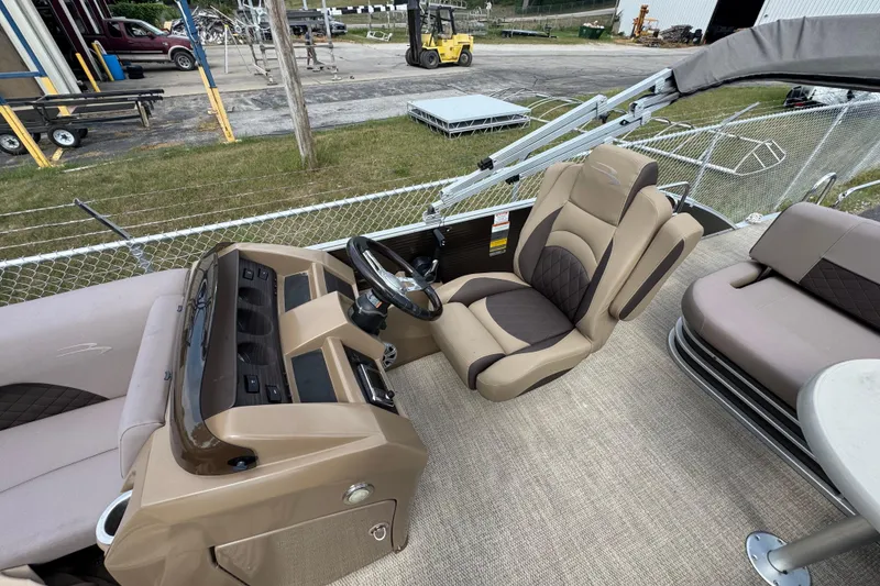 Slide: The Image of 2018 Bennington 23 SSBXP boat interior with beige and brown seating, steering console, and outdoor setting. - 5