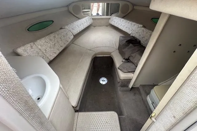 Slide: The Image of 2002 Sea Ray 225 Weekender cabin interior with seating, sink, and storage. - 10