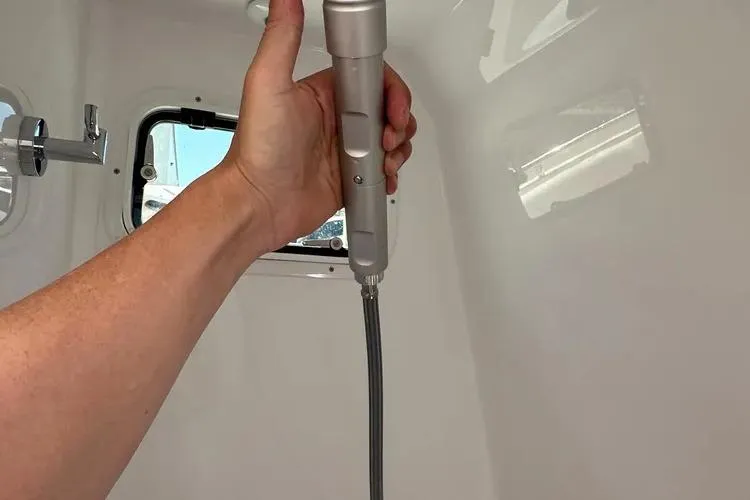 Slide: The Image of Hand holding showerhead inside 2025 HCB 42 Lujo boat bathroom. - 13