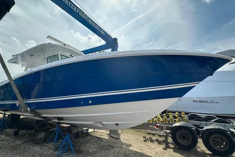Slide: The Image of 2025 HCB 42 Lujo boat in blue and white, displayed on a trailer at a marina. - 9