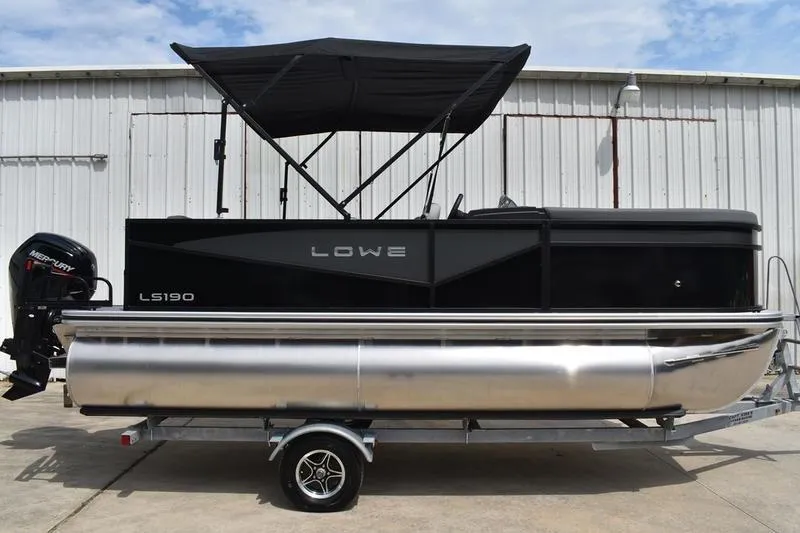 Slide: The Image of 2026 Lowe LS 190 pontoon boat with Mercury outboard motor, parked on trailer. - 2