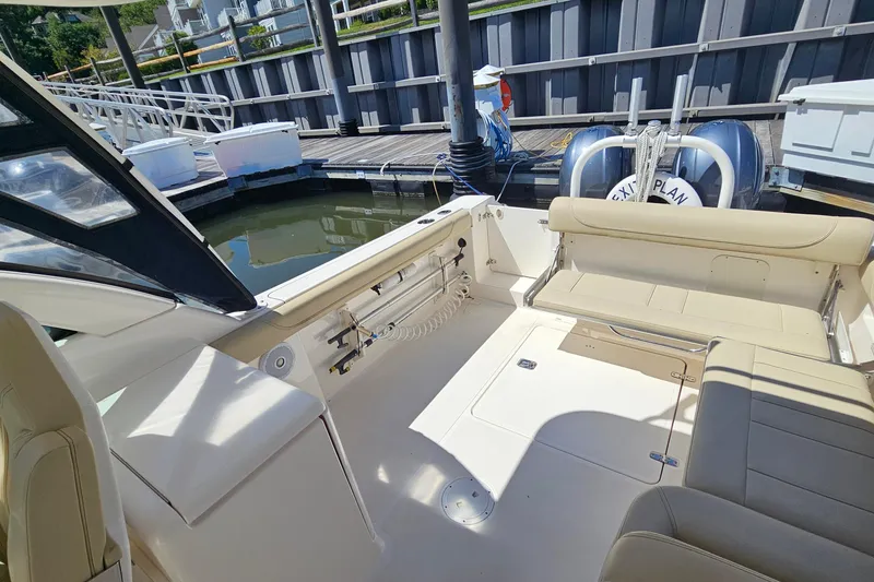 Slide: The Image of 2016 Pursuit DC 265 Dual Console boat interior at dock, featuring beige seating and storage. - 12