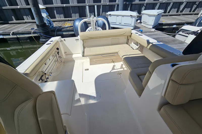 Slide: The Image of 2016 Pursuit DC 265 Dual Console boat interior with beige seating at dock. - 13