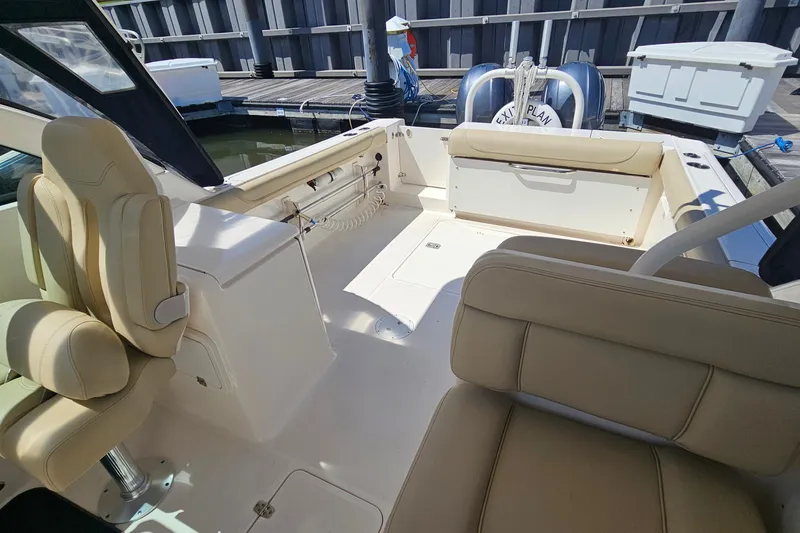 Slide: The Image of 2016 Pursuit DC 265 Dual Console boat interior with beige seating and docked at marina. - 14