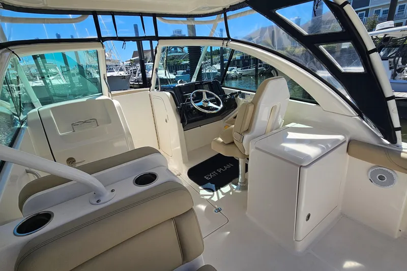 Slide: The Image of 2016 Pursuit DC 265 Dual Console boat interior with helm, seating, and marina view. - 15