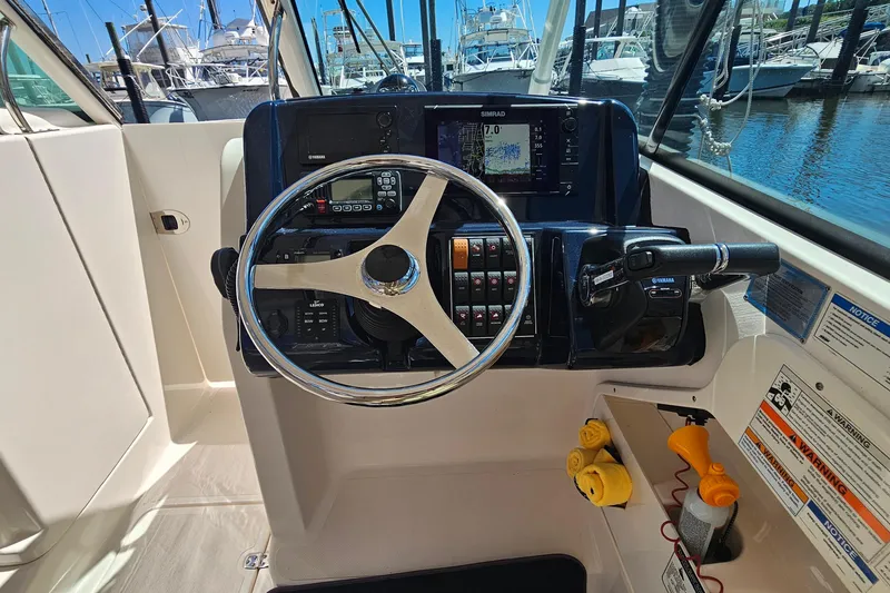 Slide: The Image of 2016 Pursuit DC 265 Dual Console boat helm with steering wheel and navigation controls. - 18