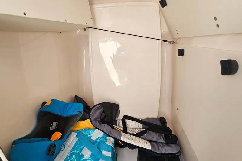 Slide: The Image of Storage compartment of 2016 Pursuit DC 265 Dual Console with life jackets. - 21
