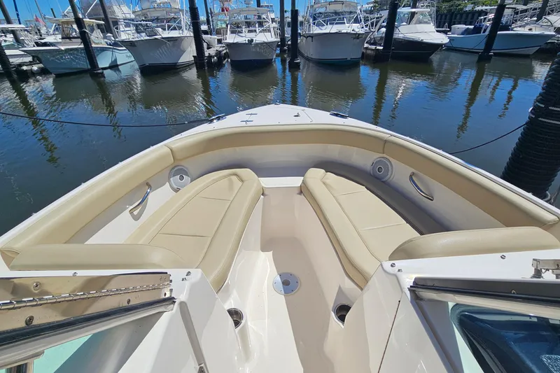 Slide: The Image of 2016 Pursuit DC 265 Dual Console boat interior with beige seating at marina. - 22